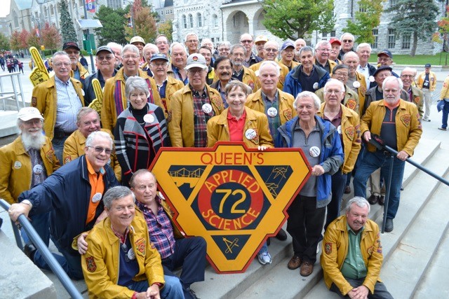 Members of Sc'72 surround a large print out of their class crest.