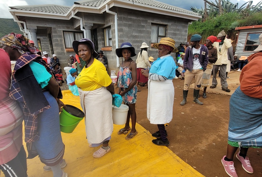 Several women lining up to receive monthly food rations for their households. 