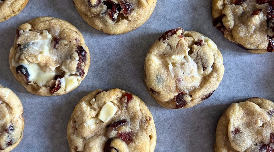 A close-up of white chocolate cranberry cookies, highlighting their soft texture and bits of dried cranberries throughout.
