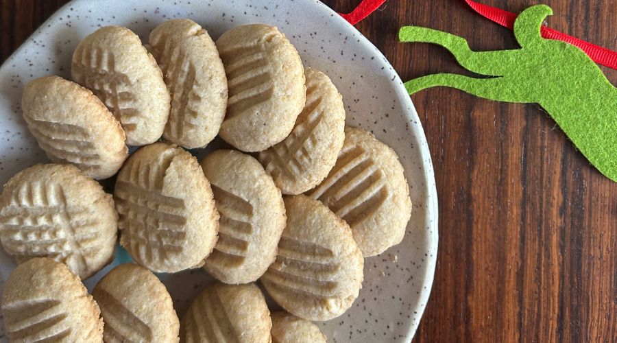 A decorative plate of Mary’s Shortbread Cookies with a green ribbon, set on a rustic table.