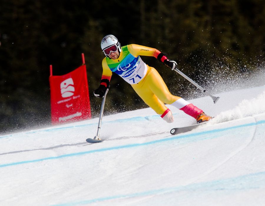 Matt Hallat, MBA’24, skiing down a slope in a yellow and blue suit during the 2010 Winter Paralympics.