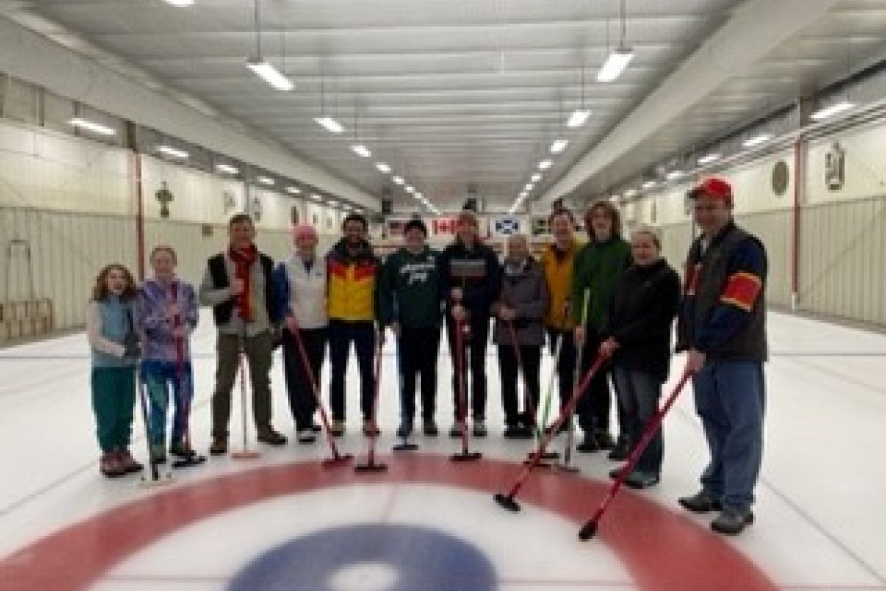 Alumni posing on a curling rink.