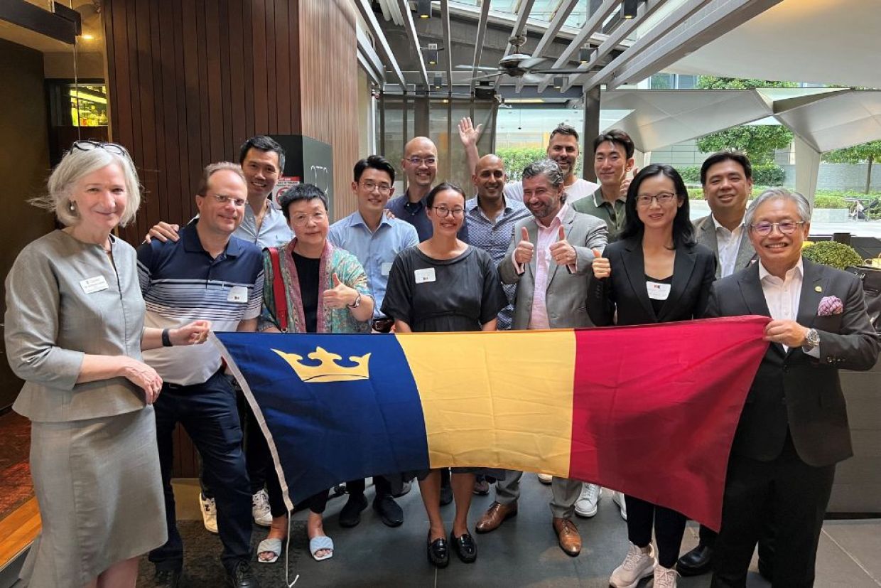 Alumni holding the Queen's tricolour flag at an event.
