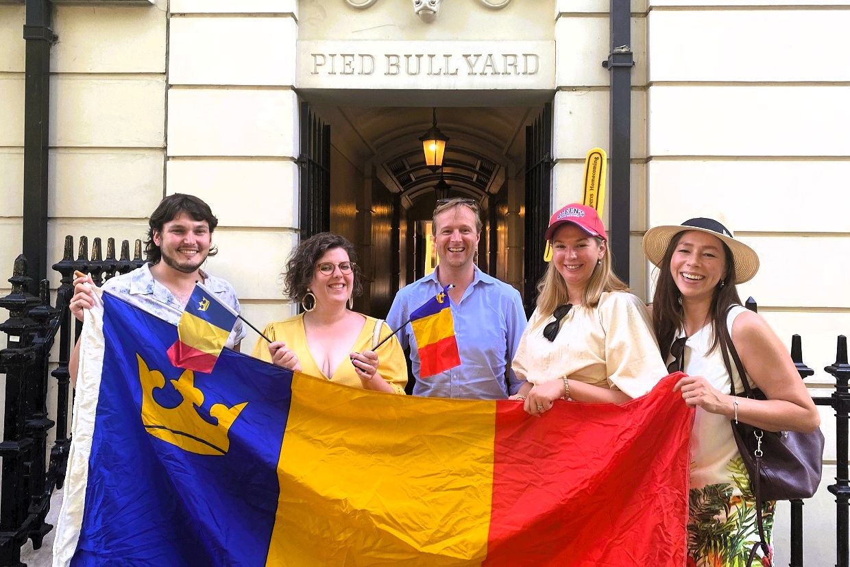 Smiling Alumni holding the tricolor flag in the UK 