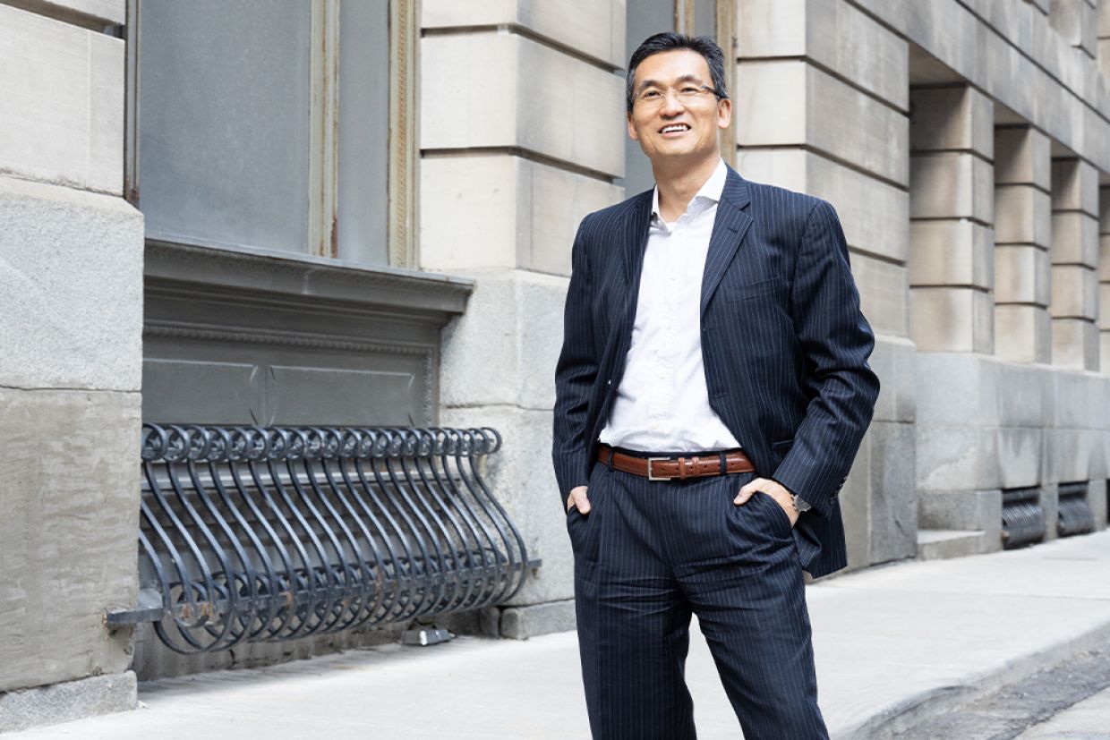 William Chung standing outside an old building in Toronto, with his hands in his pockets.