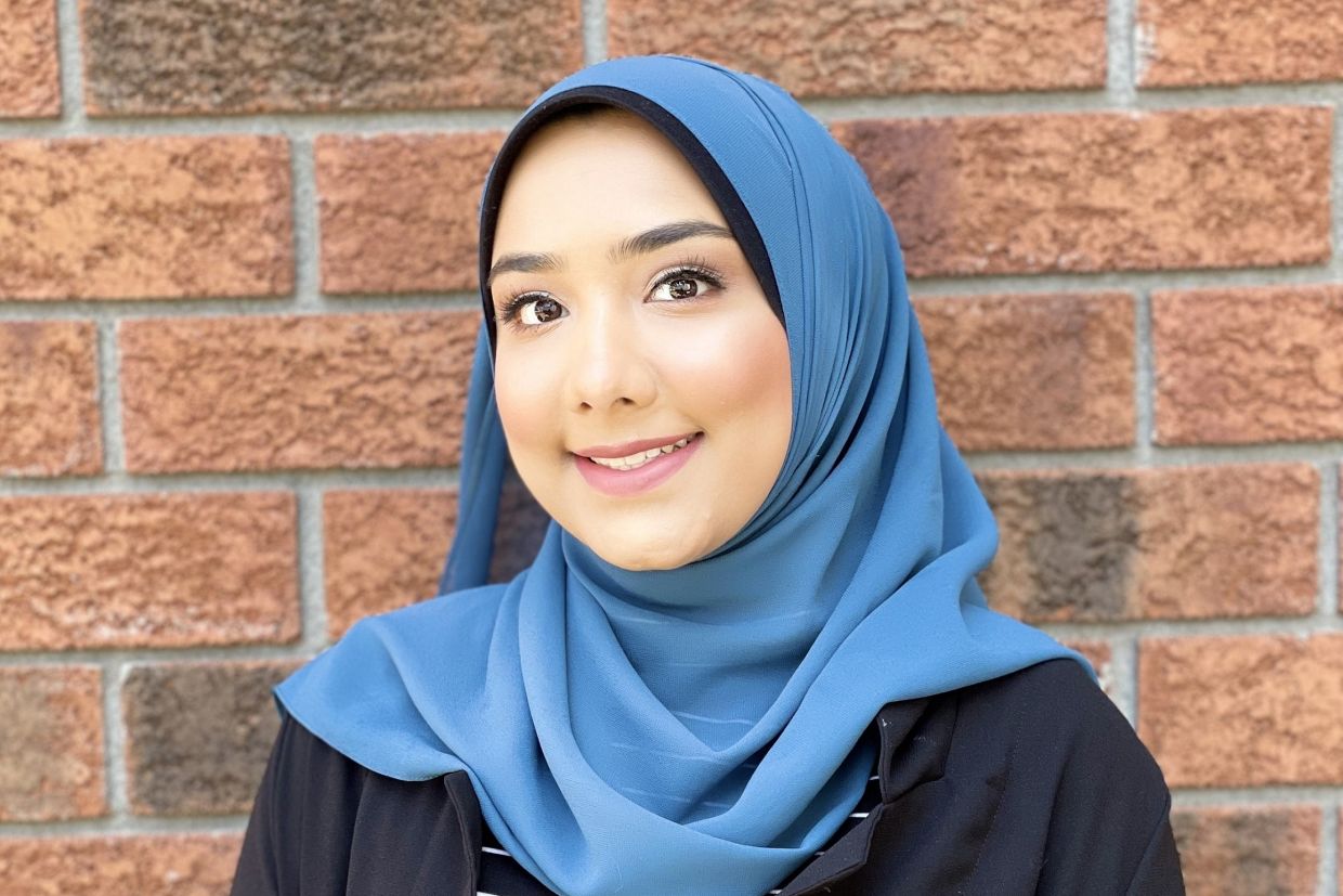 Headshot of Aelea Syed with a brick wall behind her. 