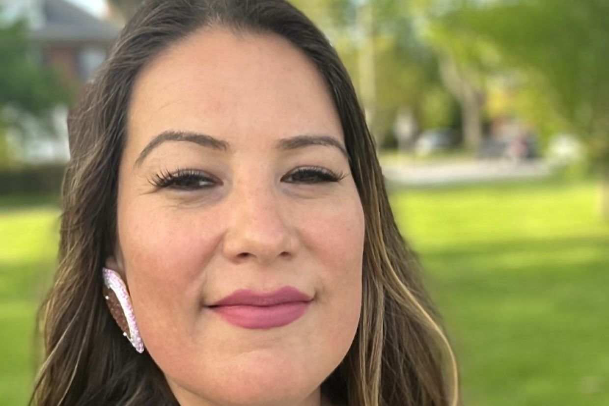 A headshot of a smiling Natasha Stirrett, who is outside with green grass behind her. 