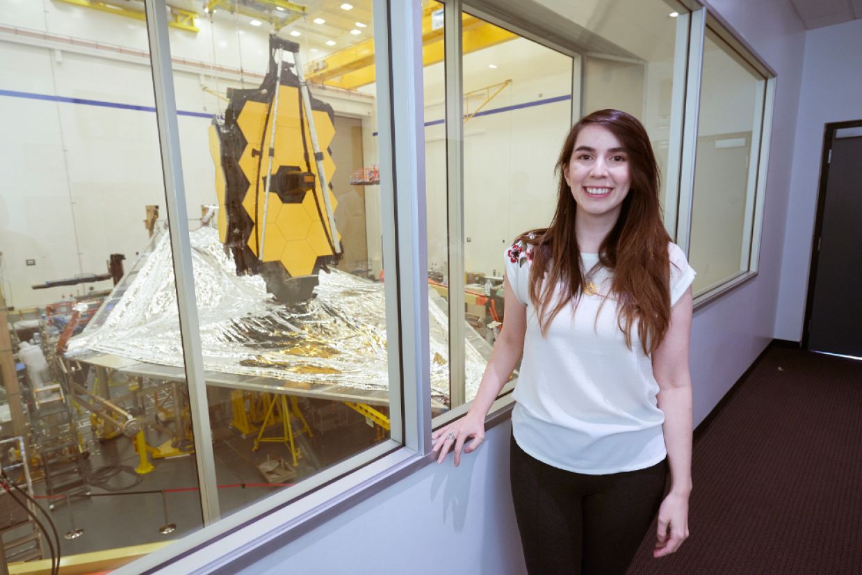 Dr. Nathalie Nguyen-Quoc Ouellette, MSc’13, PhD’17, stands in front of the James Webb Space Telescope in 2019.
