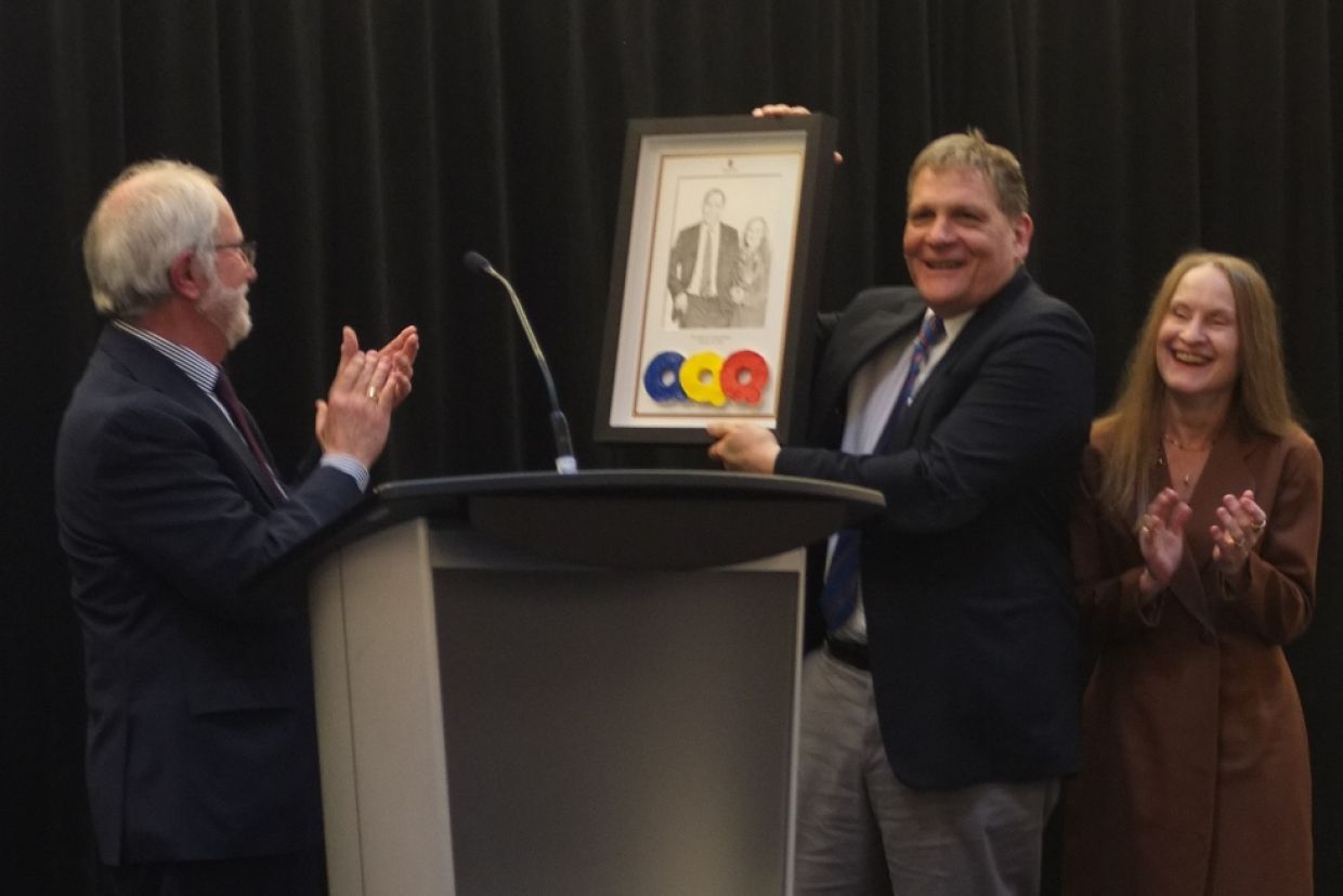 Principal and Vice-Chancellor Patrick Deane (left), presents a drawing to Principal Emeritus Daniel Woolf and his wife Julie Gordon-Woolf..