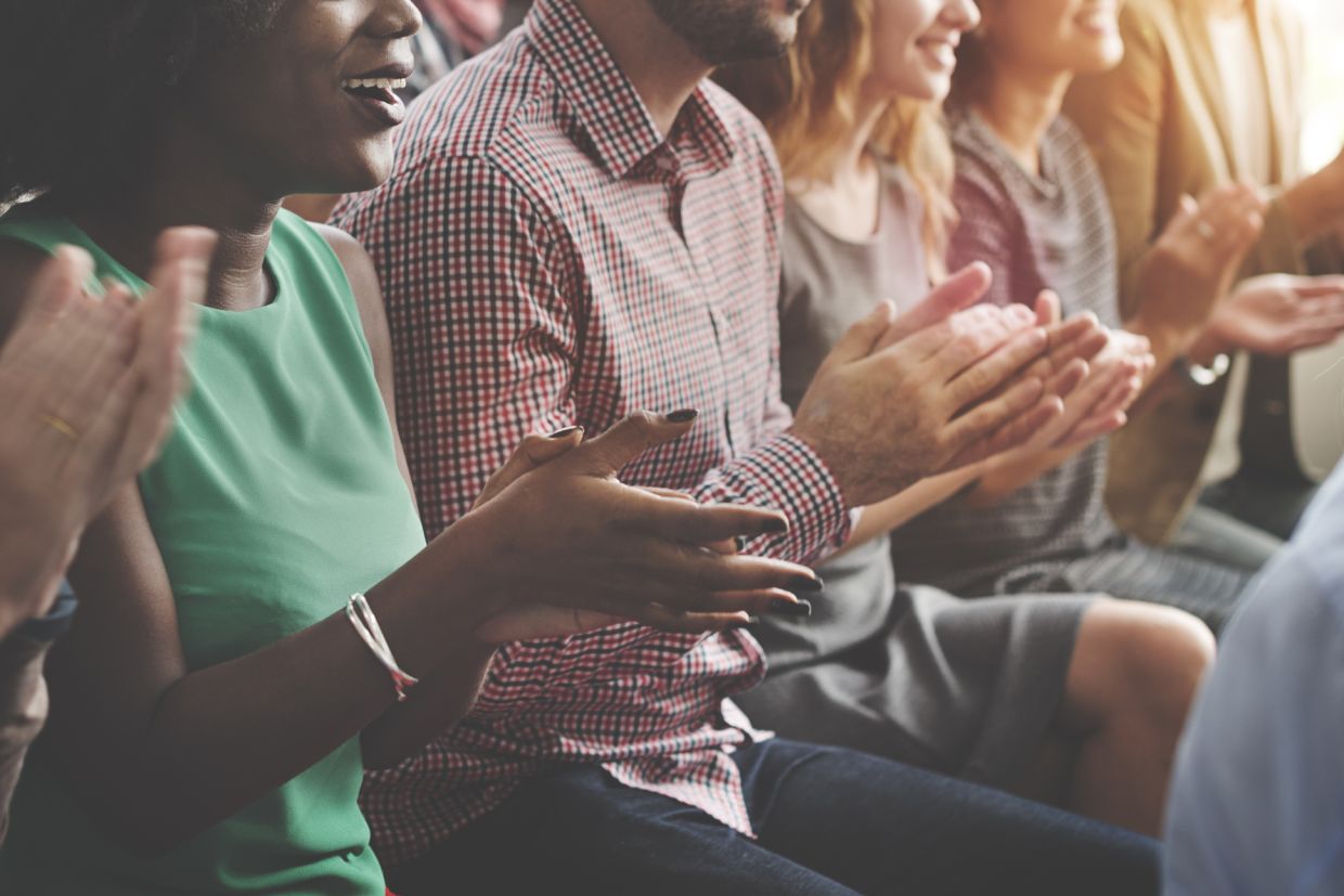 People sitting in a row clapping