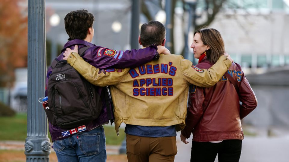 Queen's alumni walking together wearing their university gear.