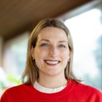 Allison Williams smiling wearing a red sweater