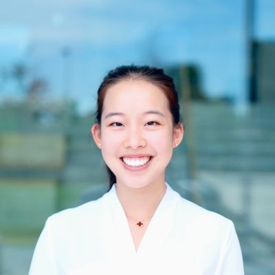 Angela smiling. She is wearing a white shirt and a red necklace