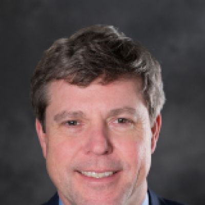 Toby smiling. He is wearing a blue shirt and jacket with a red tie