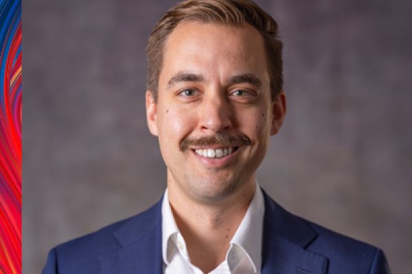 photo of Colin McLeod smiling, wearing a white shirt and blue suit jacket