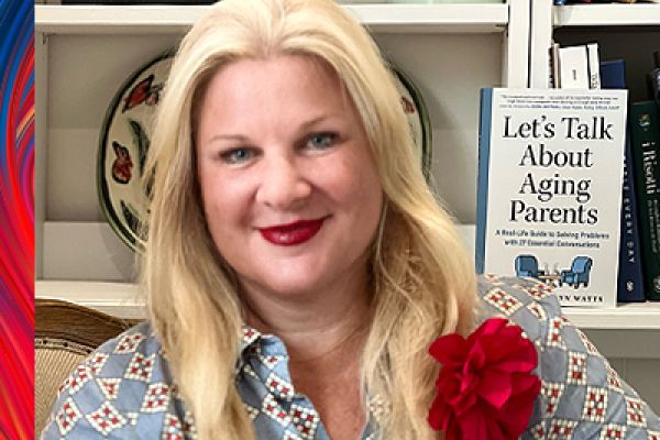 Laura Tamblyn Watts looking at the camera smiling, Laura is wearing a blue collared shirt with a diamond pattern and a read flower. in the background is a book titled "Let's Talk About Aging Parents" by Laura Tamblyn Watts