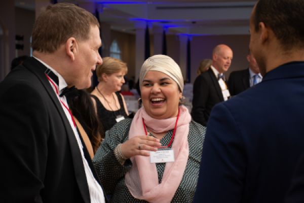 People in formal attire converse and laugh.