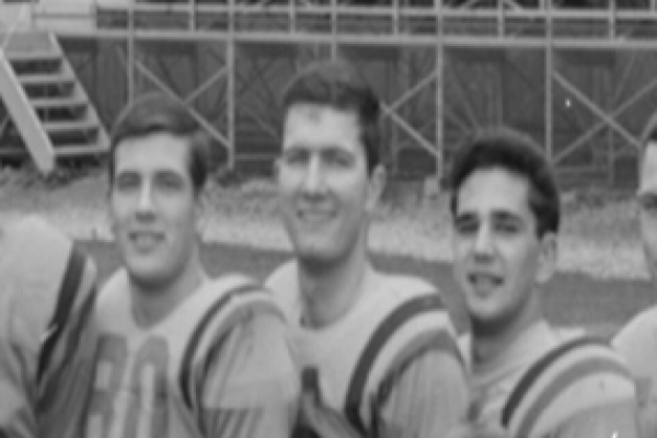 Black and white photo of Bob Howes between teammates in Queen's Football team photo.