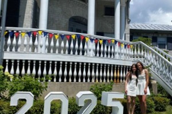 2025 with two graduates in white dresses outside Summerhill