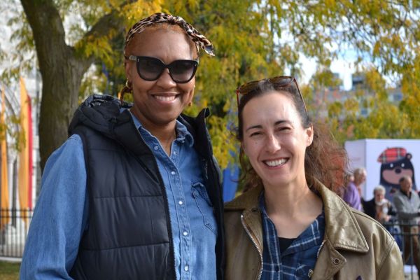 Johnelle Lanham and Kendra Hartley smile for the camera in front of a lush green tree.