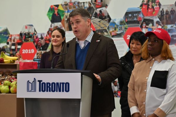Ryan Noble at a podium announces Toronto's win in the Bloomberg Philanthropies Mayors Challenge for a school food program.