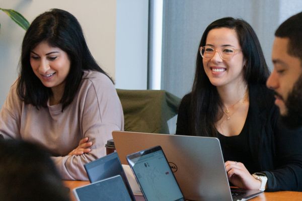 Students smiling with laptops around them.