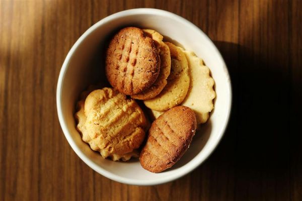 A decorative bowl of freshly baked cookies sits on a table, showcasing a variety of flavors and textures.