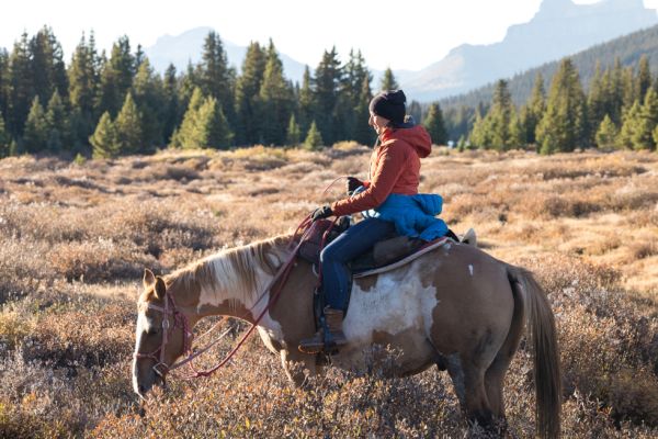Meghan J. Ward, Artsci’07, sits on a horse with a mountainscape behind her.