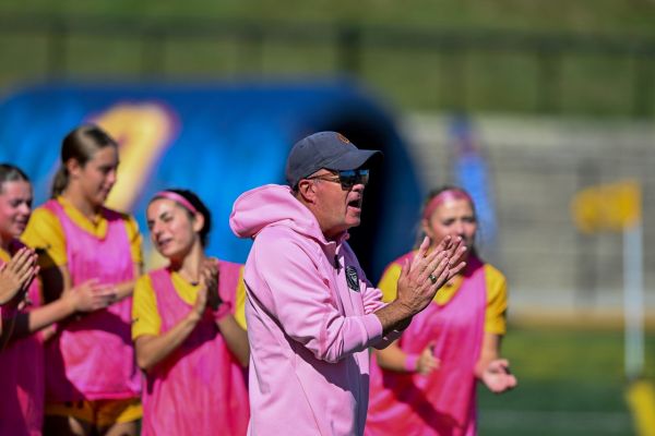 Dave McDowell clapping on the sidelines of a soccer game.
