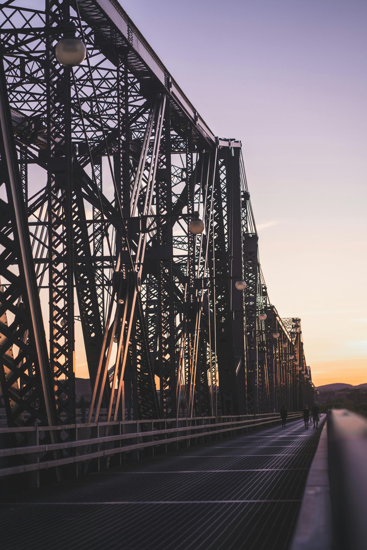 people walking on a bridge during sunset