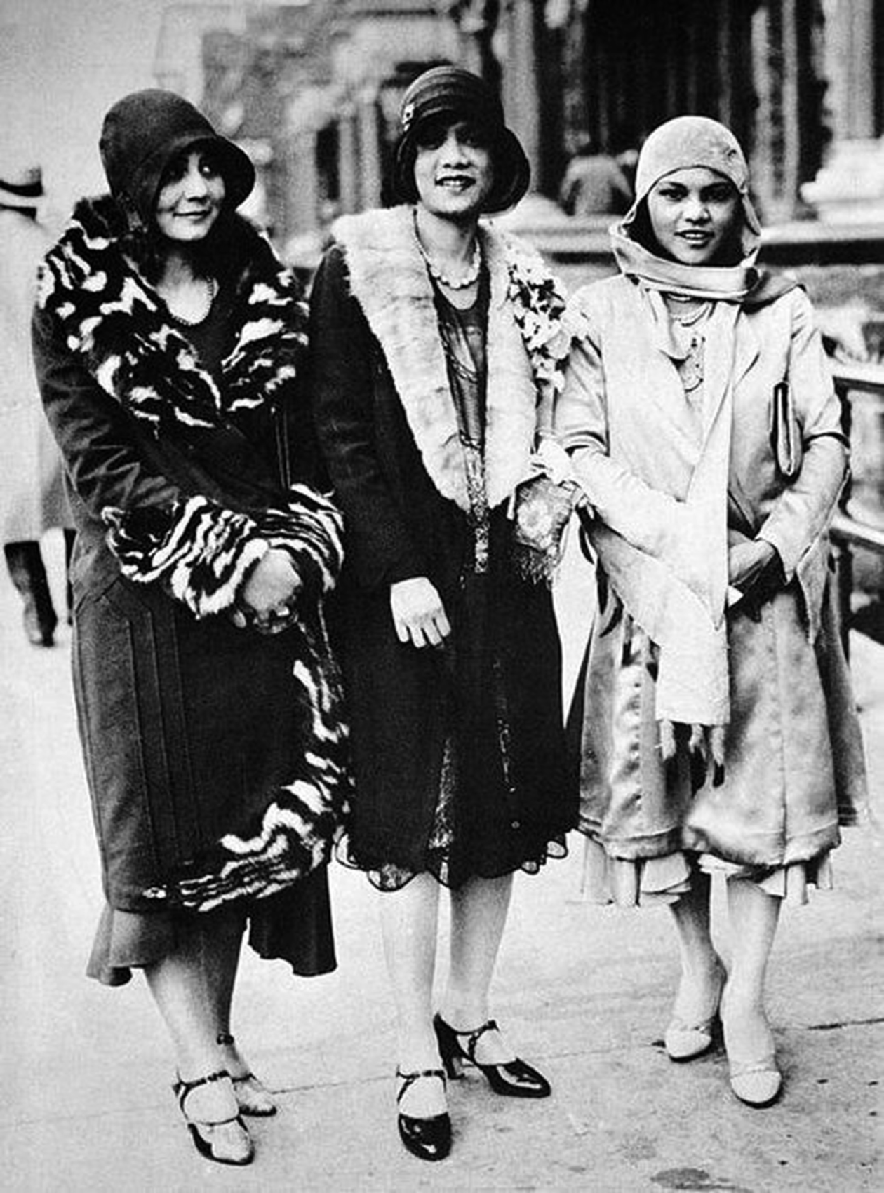 Three women posing in the middle of the street in black and white 