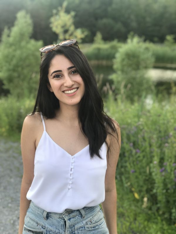 A photo of Nikta in front of a lake and greenery. 