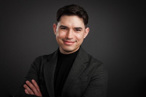 Headshot of Ian M. Clark wearing a grey suit against a dark background.
