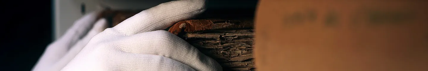 Photo of a hand in white gloves taking an old book