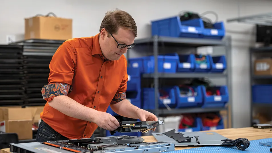 Photo of Dr. Ryan Grant assembling computer hardware at a workbench.